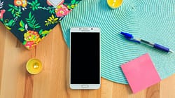 white Samsung Galaxy smartphone on top of blue place mat near blue click pen